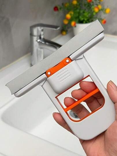 White and orange mini foldable squeeze mop held over a bathroom sink